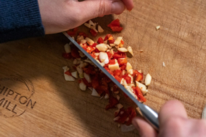 Chilli and garlic being sliced thinly together